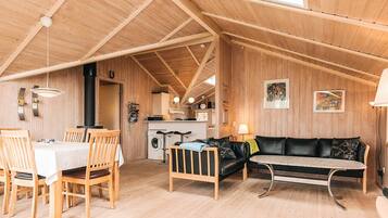 A wooden interior with a dining area, a sofa, and a kitchen.