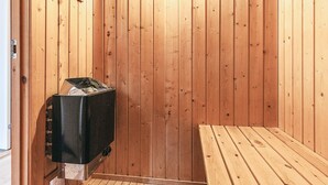 Ein Saunaraum mit Holzwänden, einer Sitzbank und einer Saunaanlage.