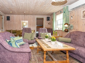 Una habitación acogedora con paredes de madera, un sofá morado, una mesita de madera y una alfombra estampada.