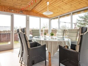 Un patio cubierto con muebles de mimbre, una mesa con mantel y un ventilador de techo.