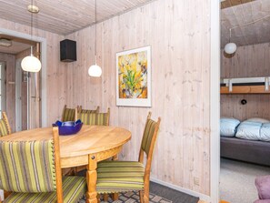 Une pièce avec une table à manger en bois, des chaises à rayures, un tableau encadré et un lit superposé.