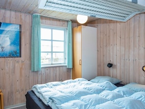 Un dormitorio con cama, ventana con cortinas, armario y un cuadro en la pared.