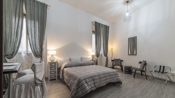 A bedroom with a bed, bedside tables, a desk, and a chair. - Villa Albani Apartment (Rome)