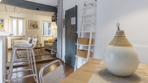 Ein modernes Interieur mit einer großen weißen Vase, Metallstühlen und einem Holztisch.