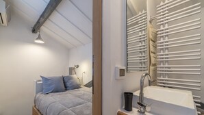 Ein Schlafzimmer mit einem Bett, einem Nachttisch, einem Spiegel und einer Heizung.