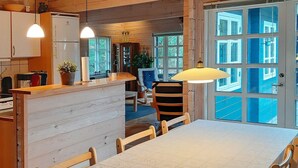 A wooden interior with a dining table, chairs, a kitchen area, and large windows. - Spacious Holiday Home With Sauna in Logstor (Logstor)
