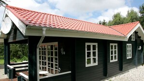 A black wooden building with a red tiled roof, white-framed windows, and a clock on the left side. - Spacious Holiday Home With Sauna in Logstor (Logstor)