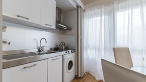 Una cocina moderna con electrodomésticos de acero inoxidable, lavadora y comedor con mesa y sillas.