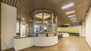 Un área de recepción moderna con un mostrador curvo, cerramiento de vidrio e iluminación colgante.
