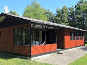 A single-story building with a red exterior, large windows, and a covered porch area. - 6 Person Holiday Home in Hals (Hals)