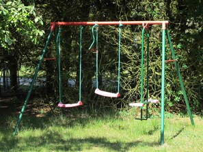 A swing set in a grassy area with trees in the background.