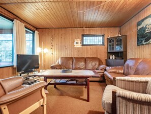 A cozy living room with leather sofas, a flat-screen TV, and a wooden ceiling.