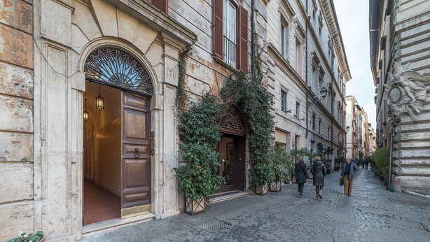 A cobblestone street with historic buildings, a large wooden door, and a wrought iron gate. - Piazza Navona Panoramic Penthouse (Rome)