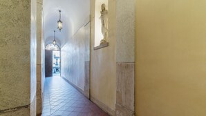 A corridor with tiled flooring, a statue on the wall, and hanging lights. - Piazza Navona Panoramic Penthouse (Rome)