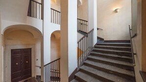 A multi-level interior with a central staircase, multiple balconies, and a dark wooden door. - Piazza Navona Panoramic Penthouse (Rome)