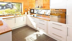 A modern kitchen with white cabinets, a wooden countertop, and a stone backsplash. - 8 Person Holiday Home in Aseral (Aseral)