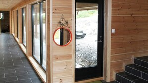 A wooden interior hallway with large windows, a door with a mirror, and a tiled floor. - 8 Person Holiday Home in Aseral (Aseral)