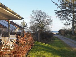 Un sendero que conduce a una playa, con un área de estar techada y vistas al mar.
