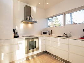 Una cocina moderna con muebles blancos, horno de acero inoxidable, microondas y ventana que proporciona luz natural.