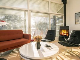 Una sala de estar moderna con un sofá, una mesa redonda con un florero y una chimenea.