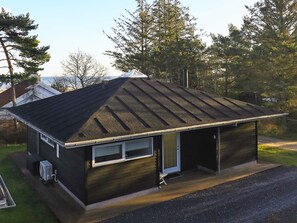 A small, single-story building with a sloped roof, a garage door, and a small porch area. - 5 Star Holiday Home in Hals (Hals)
