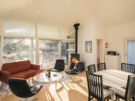 A modern living room with a fireplace, large windows, and a dining area.