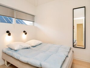 A bedroom with a bed, two wall-mounted lights, a window with blinds, and a mirror on the wall. - 5 Star Holiday Home in Hals (Hals)