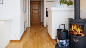 Una sala de estar moderna con estufa de leña, chimenea blanca y un pasillo que conduce a otra habitación.
