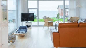 Un salón espacioso con un ventanal grande, un televisor, un sofá y una silla.