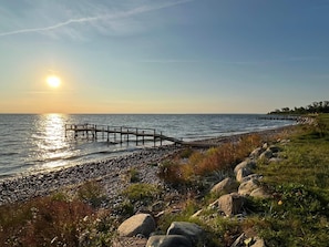 A coastal scene with a wooden pier extending into the water, a rocky shoreline, and a clear sky. - 6 Person Holiday Home in Frorup (Frørup)