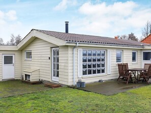 A single-story house with a sloped roof, a chimney, a front door, and a patio with a table and chairs. - 6 Person Holiday Home in Frorup (Frørup)