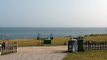 A paved pathway leading to a grassy area with a view of the sea.