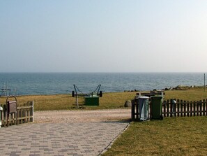 A paved pathway leading to a grassy area with a view of the sea. - 6 Person Holiday Home in Frorup (Frørup)