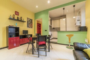 Un salon moderne comprenant un coin repas, une cuisine et un fauteuil rouge et noir avec un coussin rouge.