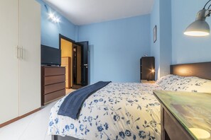 Une chambre à coucher avec un lit, une commode, un téléviseur et une lampe de bureau.