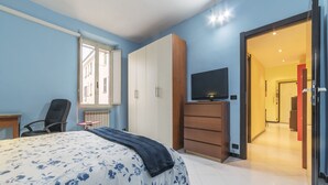 A bedroom with a bed, a TV, a wardrobe, and a chair. - Pigneto Colourful Apartment (Rome)