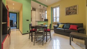 A modern living room with a dining area, a sofa, and a coffee table. - Pigneto Colourful Apartment (Rome)