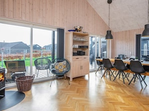 A modern kitchen with a large window, wooden cabinets, and a dining area with chairs and a table.