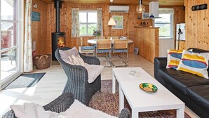 Un interior de cabaña acogedor con chimenea, comedor y zona de estar.