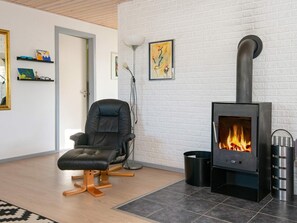 A modern living room with a black leather chair, a fireplace, and a white brick wall.