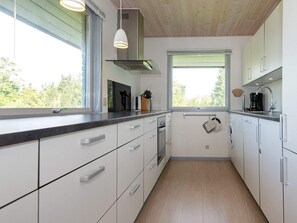A modern kitchen with white cabinets, a stainless steel range hood, and a window providing natural light.