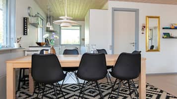 Un coin repas avec une table en bois, des chaises noires et un tapis à motifs.