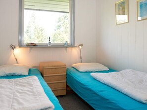 A room with two beds, a window, and a small wooden chest of drawers.