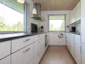 A modern kitchen with white cabinetry, a stainless steel range hood, and a window providing natural light. - 4 Star Holiday Home in Knebel (Knebel)