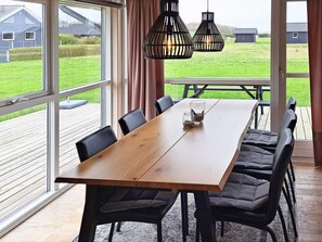 An indoor dining area with a wooden table, black chairs, and pendant lights.