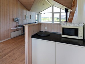A kitchen with wooden walls, a microwave, and a view of the outdoors. - Spacious Holiday Home in Storvorde near Sea (Storvorde)