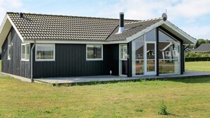 Ein modernes Haus mit dunkler Fassade, einem Ziegeldach und großen Fenstern.