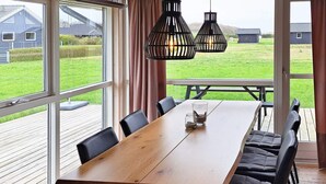 Ein Essbereich mit Holztisch, schwarzen Sitzgelegenheiten und Pendelleuchten.