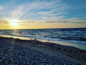 A beach with pebbles, waves, and a sunset. - 5 Star Holiday Home in Graested (Graested)