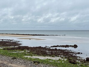 A coastal landscape with a rocky shoreline, a sandy beach, and a calm sea under a cloudy sky. - 5 Star Holiday Home in Graested (Graested)